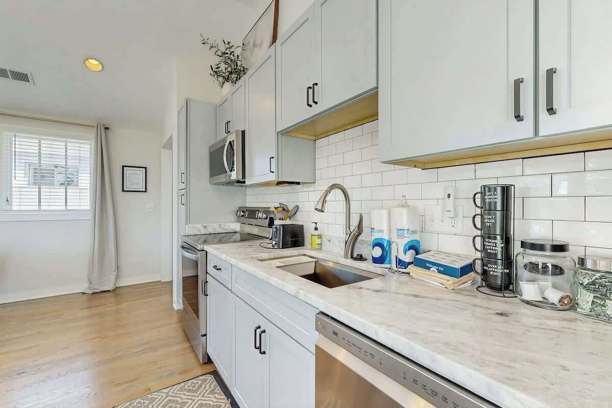 A modern kitchen with white cabinets, a stainless steel sink, and a microwave.
