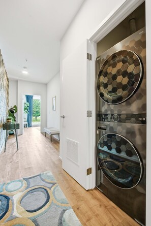 A modern hallway with a patterned glass door, a wooden floor, and a view to a room with a blue curtain. - Modern river-view condo with balcony & WiFi - walk to downtown & attractions (Nashville)