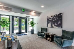 A reception area with a modern design, featuring a large abstract painting, two potted plants, and a seating area with two chairs. - Dog-friendly treetop escape with luxe interior, seasonal pool, balcony, & WiFi (Nashville)