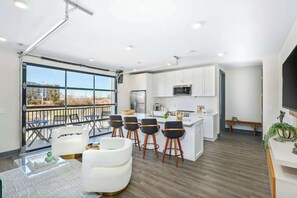 A modern kitchen with white cabinets, a central island, and bar stools. - City View 3rd Floor Condo Stay & Private Balcony (Nashville)