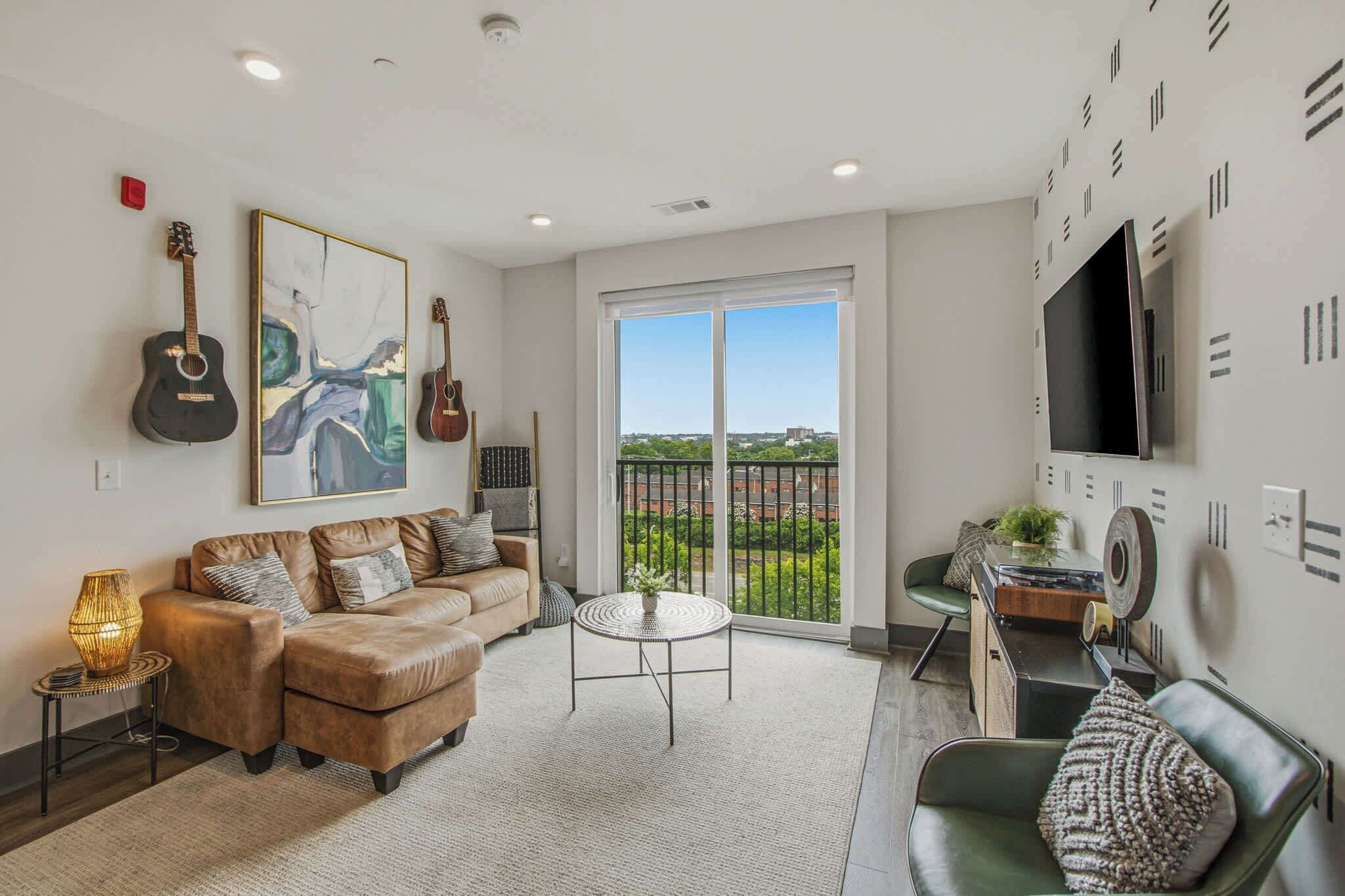 A living room with a sofa, a coffee table, a TV, and a balcony with a view.