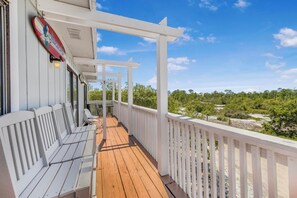 A wooden deck with white railings, a bench, and a view of a green landscape. - 🏖️ Romar Village 621 | 2BR Orange Beach Condo | Near Beach + Sleeps 4 (Orange Beach)