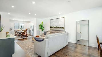 A modern living room with a sofa, dining area, and kitchen in the background.