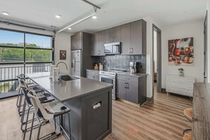 A modern kitchen with a central island, stainless steel appliances, and a view of the outdoors. - Sleek & Stylish condo with Shared Fitness Room (Nashville)