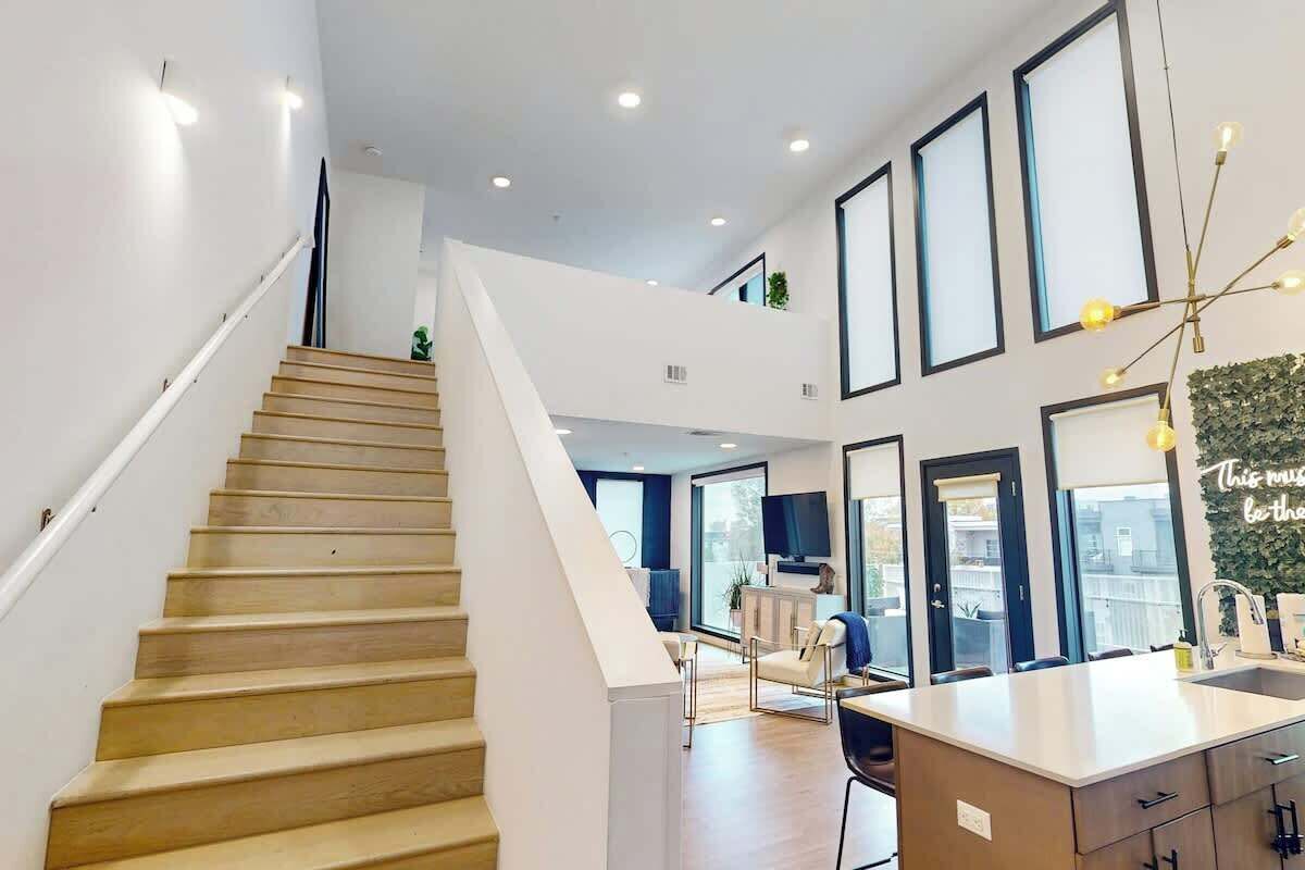 A modern interior with a staircase, a kitchen area, and a living space with large windows.