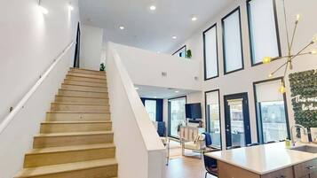 A modern interior with a staircase, a kitchen area, and a living space with large windows.