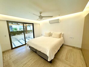 Ein Schlafzimmer mit Bett, Deckenventilator, Klimaanlage und einer Schiebetür zu einem Außenbereich.