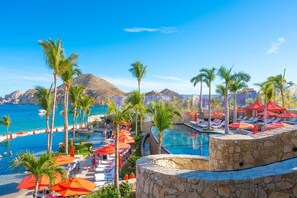 Un área de piscina en un resort con varias piscinas, palmeras y vistas a la playa.