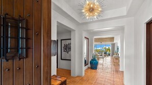 A hallway with a wooden door, a blue vase, and a tiled floor. - Newly Renovated Condo With Ocean View Luxury Amenities in Beachfront Resort Walk to Downtown (Cabo San Lucas)