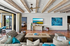 Amplia sala de estar con una televisión de pantalla plana grande, techo de madera y vistas al exterior.