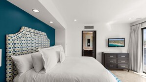 Ein modernes Hotelzimmer mit einem großen Bett, einem Fernseher, einem Schminktisch und Blick auf die Stadt.