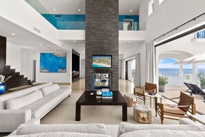 A spacious living area with a fireplace, a large flat-screen TV, and a view of the sea. - Breathtaking Villa Boasting a Private Putt Chip Course Gym Tennis Court Resort Access More (San José del Cabo)