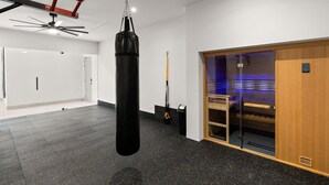 A modern gym with a punching bag, ceiling fan, and exercise equipment. - Brand New Villa BIG Ocean View Gym Close to the Beach (San José del Cabo)