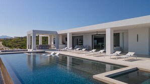 A modern pool area with lounge chairs, a bar, and a view of the landscape. - Brand New Villa BIG Ocean View Gym Close to the Beach (San José del Cabo)
