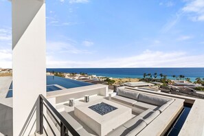 Eine Dachterrasse mit Pool, Sitzgelegenheiten im Freien und Blick auf den Ozean.