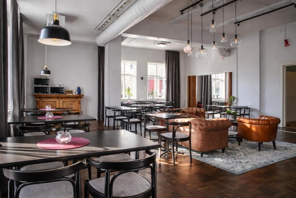 A modern dining area with a long table, multiple chairs, and pendant lighting.