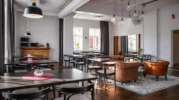 A modern dining area with a long table, multiple chairs, and pendant lighting.
