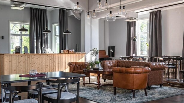 A modern living room with a dining area, leather sofas, and pendant lighting. - Wärdshuset Liden (Liden)