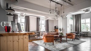 A spacious lounge area with leather sofas, a wooden counter with a drink, and a large window providing natural light. - Wärdshuset Liden (Liden)