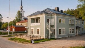 A two-story building with a spiral staircase, a church in the background, and a dirt road in front. - Wärdshuset Liden (Liden)