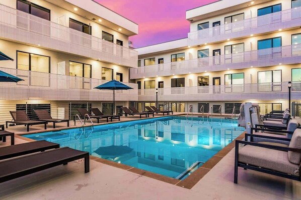 A multi-story hotel with a swimming pool, sun loungers, and a balcony with a view. - Eco-Friendly Condo with Shared Seasonal Pool, Balcony, and Free WiFi (Nashville)