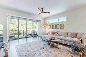 A spacious living room with a large sliding glass door, a ceiling fan, a sofa, a coffee table, and a patterned rug. - Modern Townhome, Open Living Space, Near Nashville (Nashville)