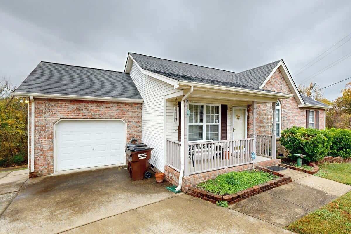A two-story house with a garage, a front porch, and a brick exterior.