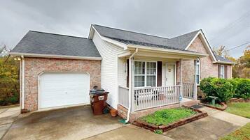 A two-story house with a garage, a front porch, and a brick exterior.