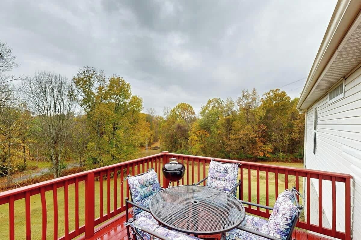 A deck with a table and chairs, overlooking a wooded area.