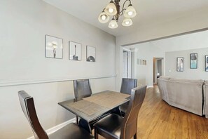 Een zithoek met een tafel, stoelen, een bank en kunst aan de muur.