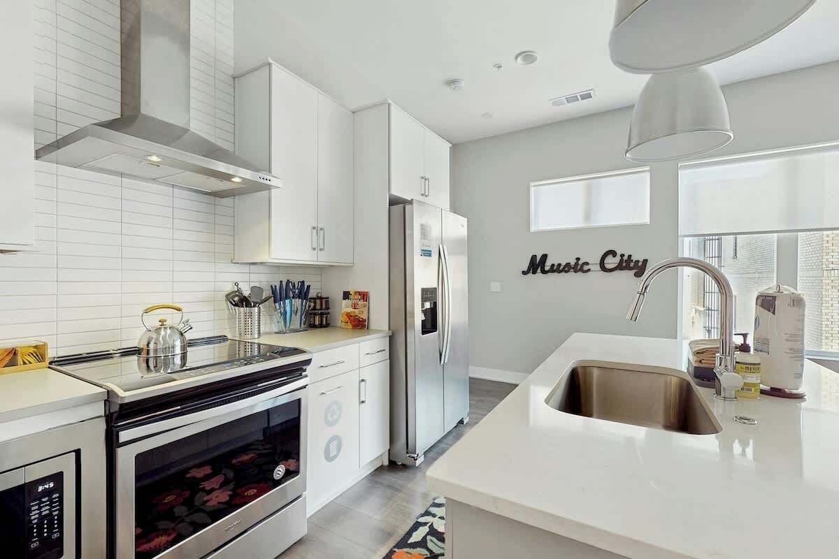 A modern kitchen with white cabinetry, a stainless steel refrigerator, and a built-in oven.