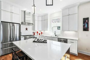 A modern kitchen with white cabinetry, stainless steel appliances, and a central island. - 4BR Music City Escape Near Broadway, Sleeps 10 (Nashville)