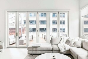 A modern living room with a white sofa, a coffee table, and a sliding glass door leading to an outdoor patio. - Charming Condo Stay with Tasteful Decor, Sleeps 4 (Nashville)