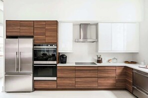 A modern kitchen with stainless steel appliances, wooden cabinetry, and white countertops. - Charming condo with central AC, full kitchen, & tasteful decor (Nashville)