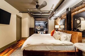 Habitación de hotel moderna con una cama grande, una pequeña mesa redonda y vistas al área de la cocina.