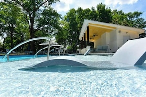 A swimming pool with a water slide, surrounded by trees and a covered seating area. - Historic East Nashville Cottage Shared Pool Gym (Nashville)