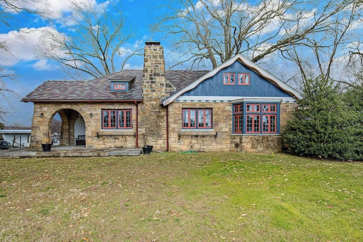 A stone house with a chimney, a porch, and a garage.