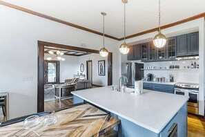 Una cocina moderna con una isla grande, luces colgantes y armarios empotrados.