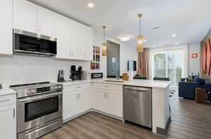 A modern kitchen with stainless steel appliances, white cabinetry, and a built-in dishwasher. - Upscale 4th-floor condo near top attractions with fast WiFi & rooftop lounge (Nashville)