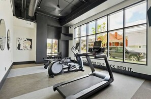 A gym with treadmills, a rowing machine, and a wall with motivational text. - Upscale 4th-floor condo near top attractions with fast WiFi & rooftop lounge (Nashville)