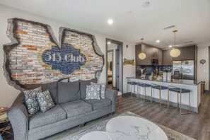 A modern interior with a sofa, a bar area, and a kitchen. - Rockstar Downtown Condo Escape & Private Balcony (Nashville)