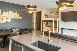 A modern kitchen with a central island, a dining area with chairs, a built-in bench, and a city skyline mural. - Second-floor Condo with High-speed WiFi & Balcony (Nashville)