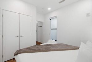 A bedroom with a bed, a wardrobe, a mirror, and a window. - Riverfront Condo Stay with Balcony, Near Downtown (Nashville)