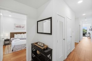 A hotel room with a bed, bedside table, and a wall-mounted mirror. - Riverfront Condo Stay with Balcony, Near Downtown (Nashville)