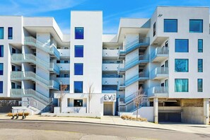 Un edificio residencial moderno de varios pisos con balcones, garaje y cielo despejado.