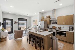 A modern kitchen with a central island, bar stools, wooden cabinets, and a stainless steel range hood. - 1.4 to DT Nashville・Stylish Gulch Escape・Pool・ Gym (Nashville)