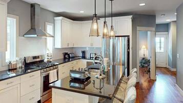 A modern kitchen with white cabinets, stainless steel appliances, and pendant lighting.