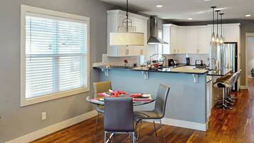 A modern kitchen with a central island, white cabinets, and a dining area with two chairs.