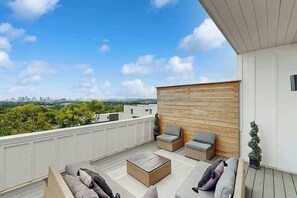 A rooftop terrace with outdoor seating, a view of the city, and a wooden wall. - Stylish townhouse with a rooftop deck, balconies, washer, dryer, & wet bar (Nashville)