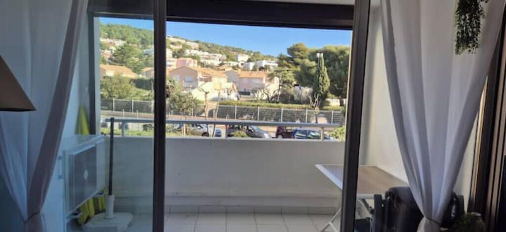 A balcony with a view of a residential area and parked cars.